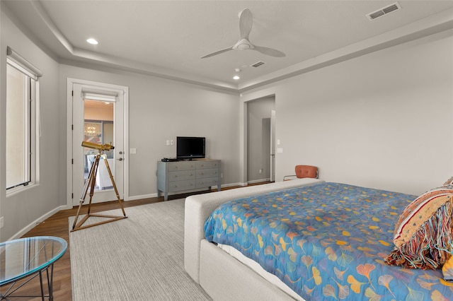 bedroom with ceiling fan, a raised ceiling, and hardwood / wood-style flooring