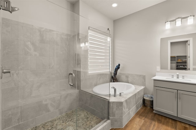 bathroom with hardwood / wood-style flooring, vanity, and separate shower and tub