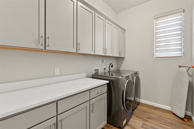 laundry area featuring light wood-type flooring, cabinets, and washing machine and clothes dryer