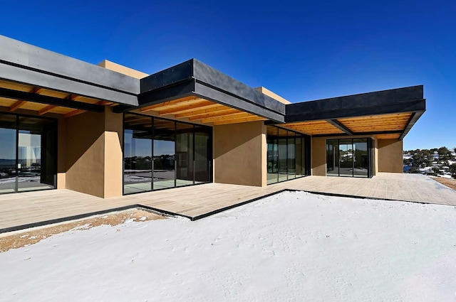 snow covered rear of property with a wooden deck