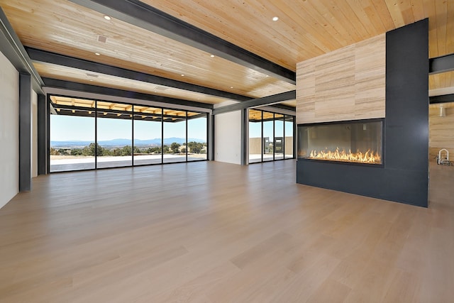 unfurnished living room with wood finished floors, a healthy amount of sunlight, a fireplace, wood ceiling, and expansive windows