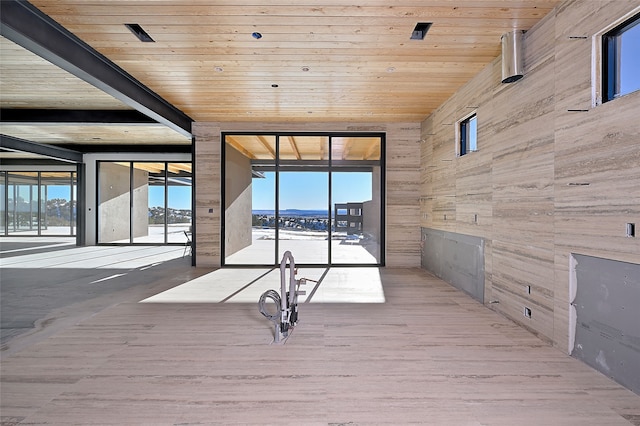 interior space featuring beamed ceiling, wood finished floors, wooden ceiling, and wood walls