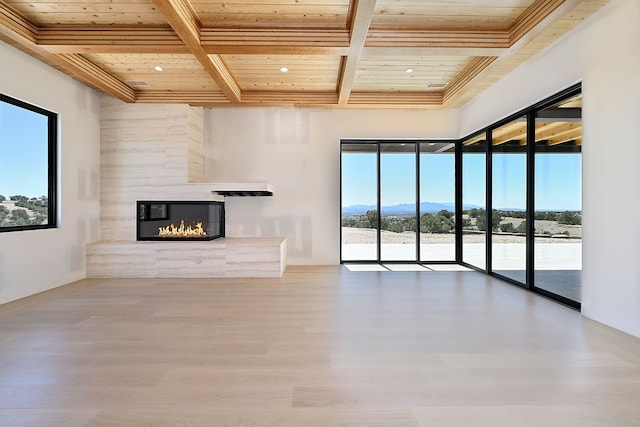 unfurnished living room featuring wood ceiling, beam ceiling, a fireplace, wood finished floors, and coffered ceiling