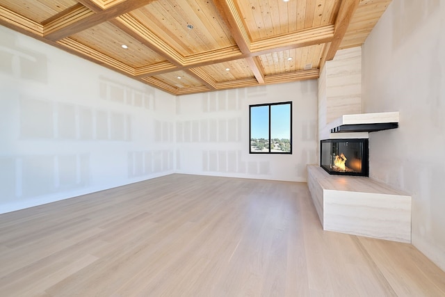 unfurnished living room with a multi sided fireplace, beamed ceiling, light wood-style flooring, wooden ceiling, and coffered ceiling