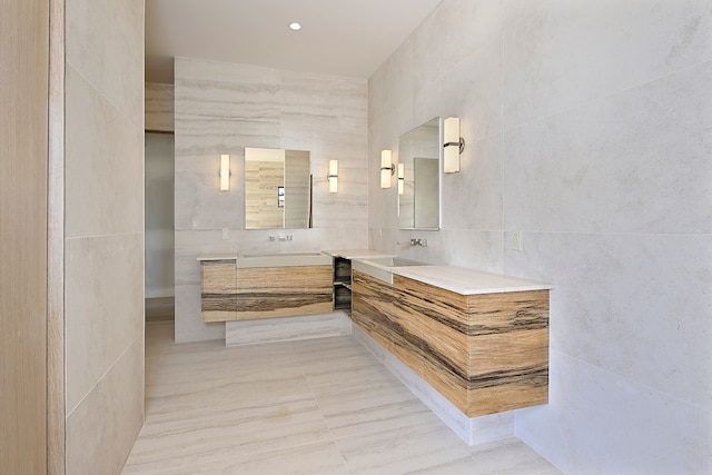 bathroom featuring a sink, tile walls, and two vanities