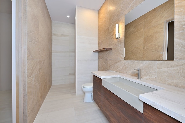 bathroom with vanity, tile walls, and toilet