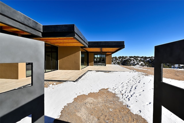 snow covered patio with a wooden deck