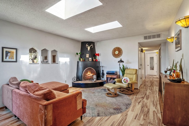 living room featuring a textured ceiling, a skylight, and light hardwood / wood-style floors