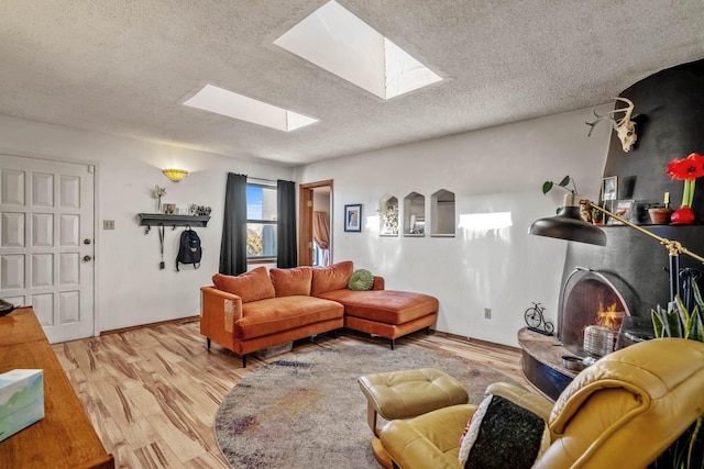 living room with a textured ceiling, a skylight, and light wood-type flooring