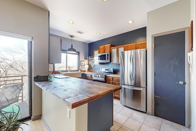 kitchen with pendant lighting, stainless steel appliances, sink, kitchen peninsula, and light tile patterned floors