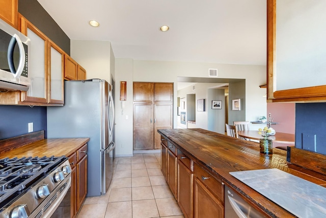 kitchen with light tile patterned floors, appliances with stainless steel finishes, and wooden counters