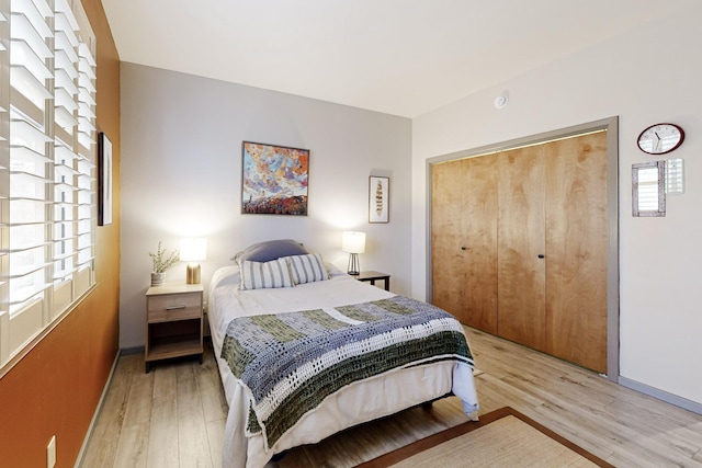 bedroom with multiple windows, a closet, and light hardwood / wood-style flooring