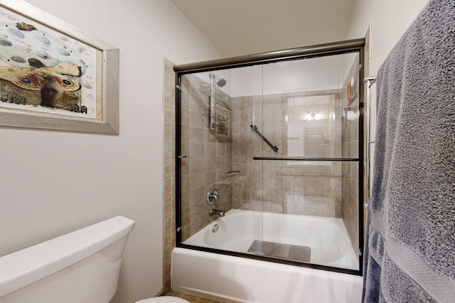 bathroom featuring toilet and shower / bath combination with glass door