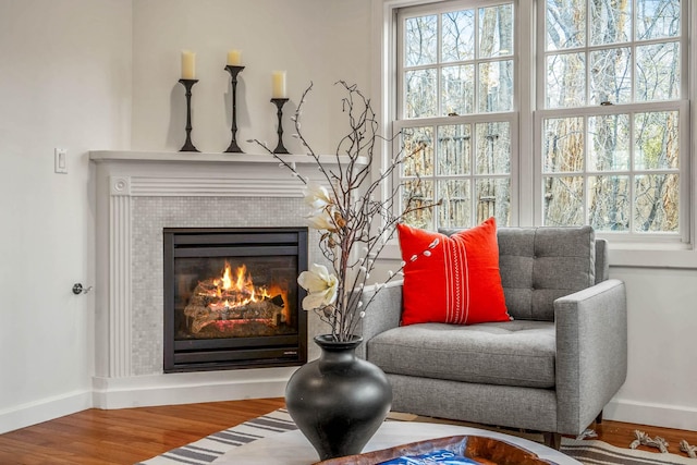 sitting room featuring a tiled fireplace, a wealth of natural light, and hardwood / wood-style floors