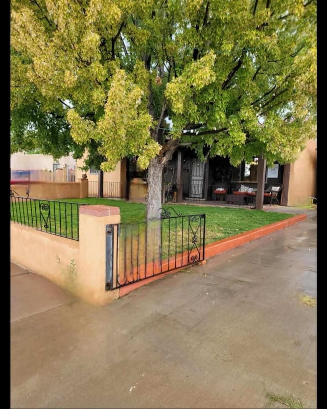 exterior space featuring a fenced front yard, a gate, a front lawn, and stucco siding