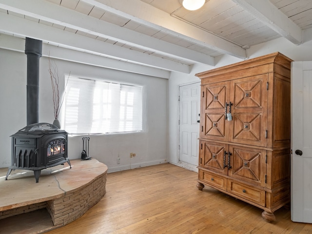 sitting room with wood ceiling, a wood stove, beamed ceiling, and light wood-type flooring