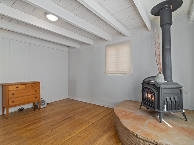 interior space featuring wooden ceiling, wood walls, a wood stove, and hardwood / wood-style flooring