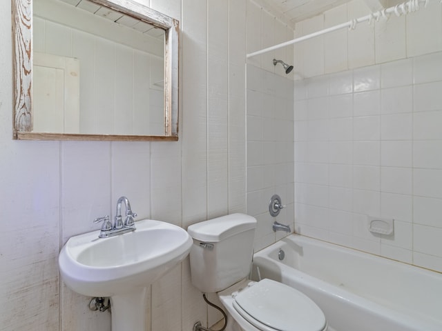 full bathroom featuring toilet, tiled shower / bath combo, tile walls, and sink