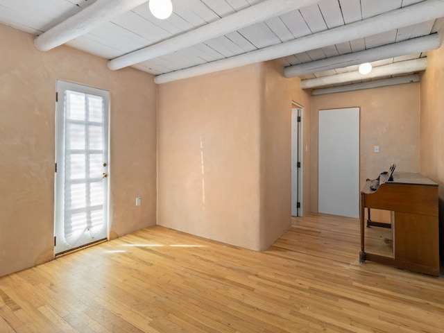 unfurnished room with beam ceiling and light wood-type flooring