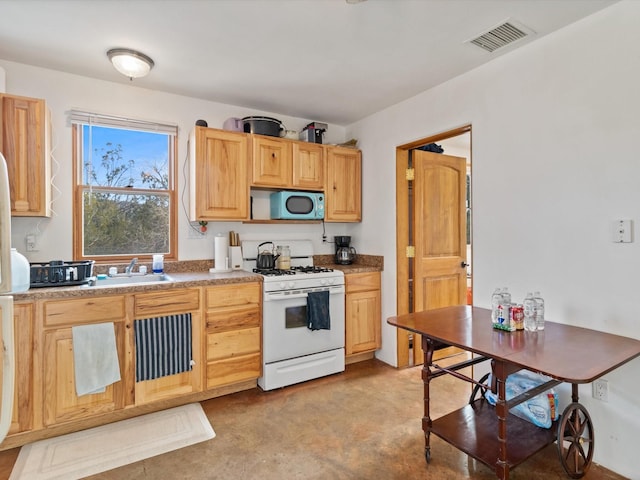 kitchen featuring white gas range oven, light countertops, a sink, light brown cabinetry, and visible vents