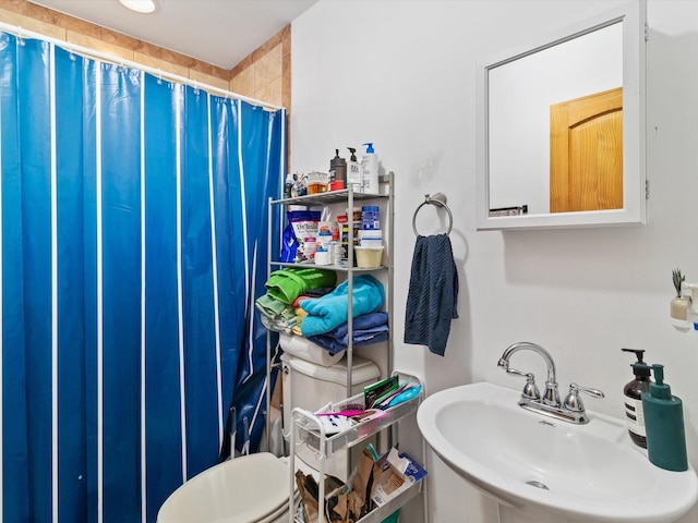 bathroom featuring toilet, a sink, and a shower with shower curtain