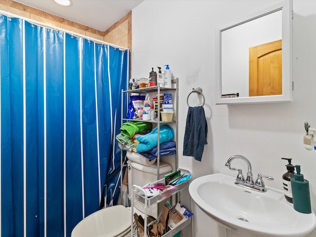 full bathroom featuring curtained shower, toilet, and a sink