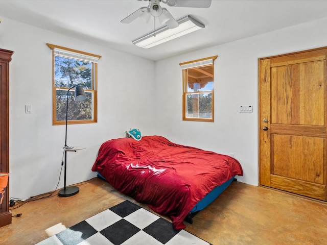 bedroom with concrete floors, ceiling fan, and multiple windows