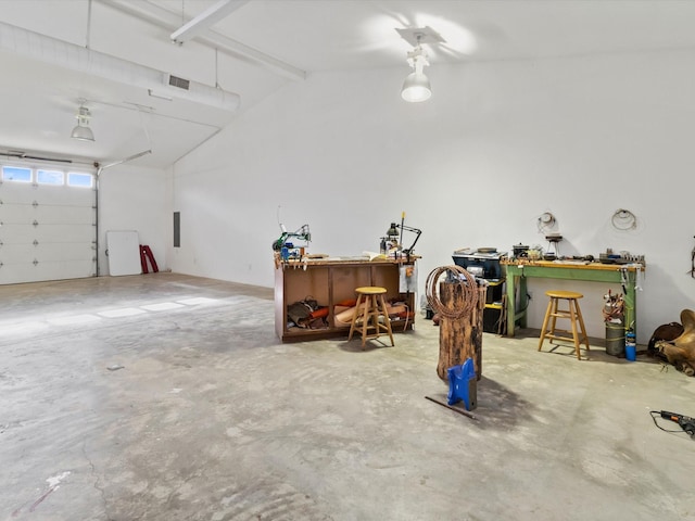 garage featuring electric panel, visible vents, and a workshop area