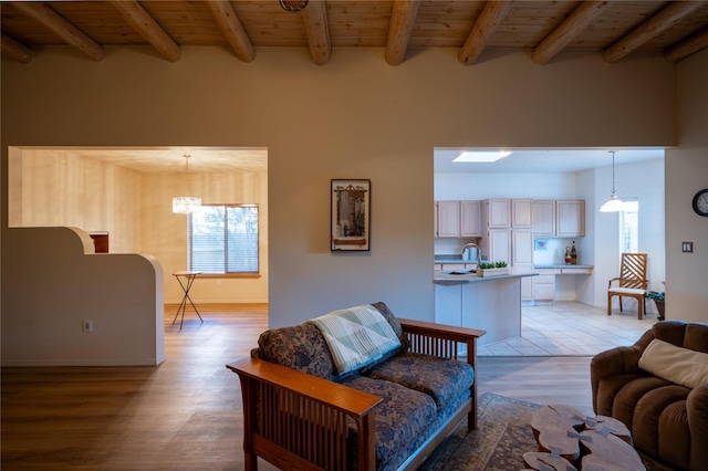 living room featuring light hardwood / wood-style flooring, a notable chandelier, beamed ceiling, and wooden ceiling