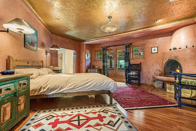 bedroom featuring wood-type flooring, wood walls, and a large fireplace