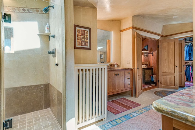 bathroom with a shower with shower door, radiator heating unit, and vanity