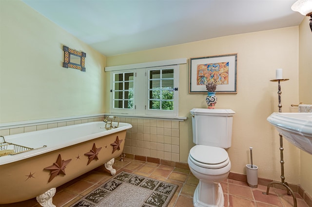 bathroom with a tub to relax in, tile patterned floors, and toilet