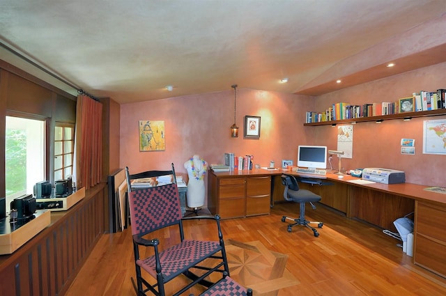 office area with built in desk, vaulted ceiling, and light hardwood / wood-style floors