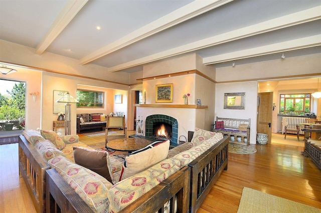 living room with light wood-type flooring, a tile fireplace, and beamed ceiling