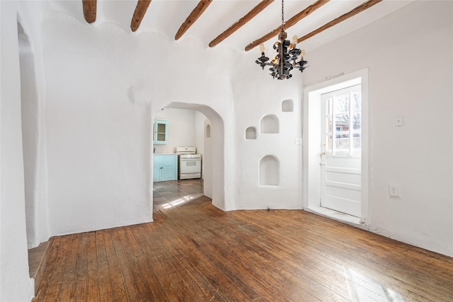 interior space with dark wood-type flooring, beam ceiling, and a notable chandelier