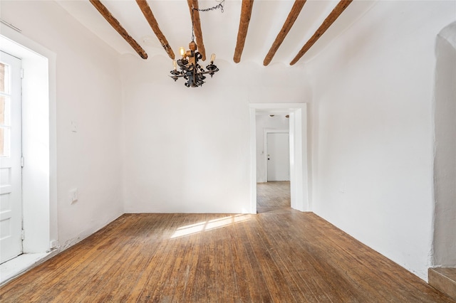 empty room with wood-type flooring, beamed ceiling, and a chandelier