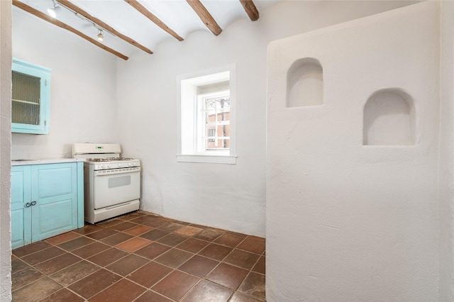 kitchen featuring white range with gas cooktop, brick ceiling, blue cabinetry, and lofted ceiling with beams