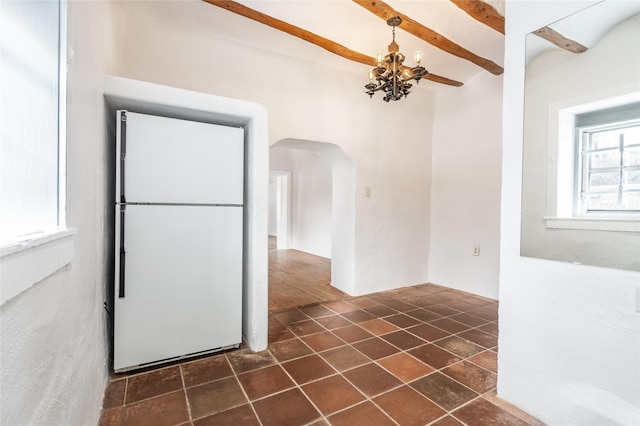 kitchen featuring beam ceiling, a chandelier, and white fridge