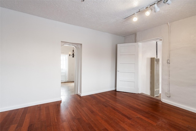 empty room featuring a textured ceiling, a chandelier, and dark hardwood / wood-style floors