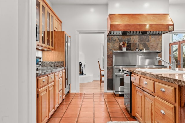 kitchen with premium range hood, decorative backsplash, sink, light tile patterned floors, and light stone counters