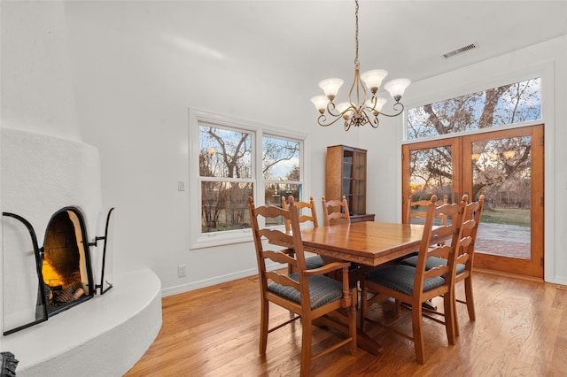 dining room featuring light wood-type flooring, french doors, and a notable chandelier