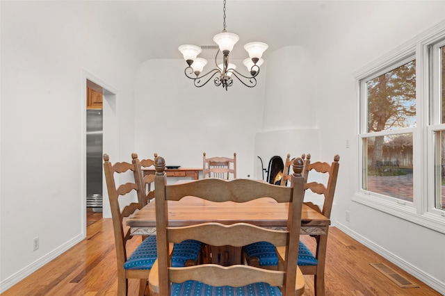 dining area with light wood-type flooring, an inviting chandelier, and a healthy amount of sunlight