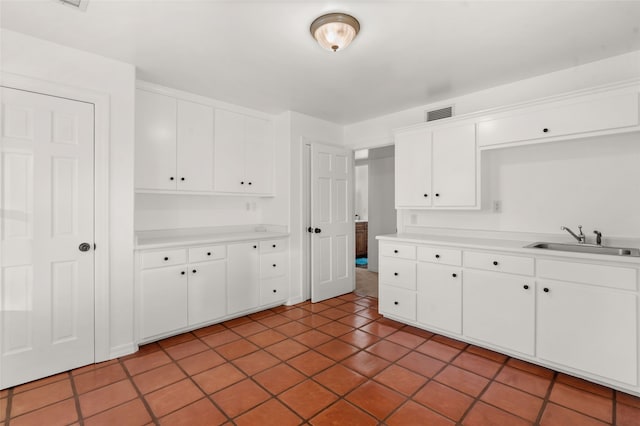 kitchen with white cabinets, sink, and light tile patterned floors