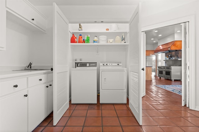 clothes washing area featuring separate washer and dryer, dark tile patterned flooring, and sink