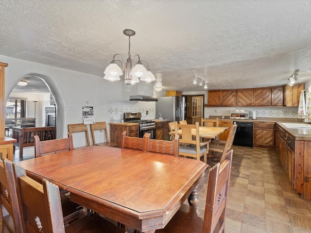 dining space featuring arched walkways, a textured ceiling, light floors, and a chandelier