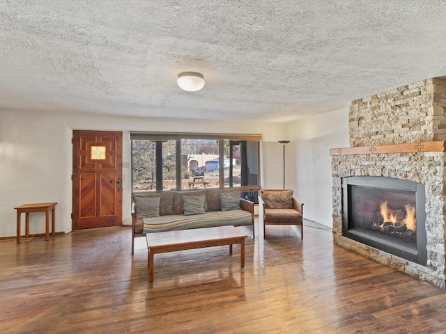 living area with a fireplace, wood-type flooring, and a textured ceiling