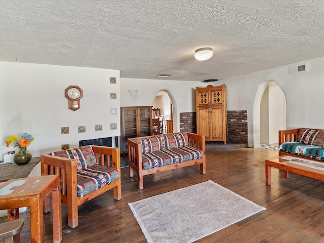 living room featuring hardwood / wood-style flooring, visible vents, and arched walkways