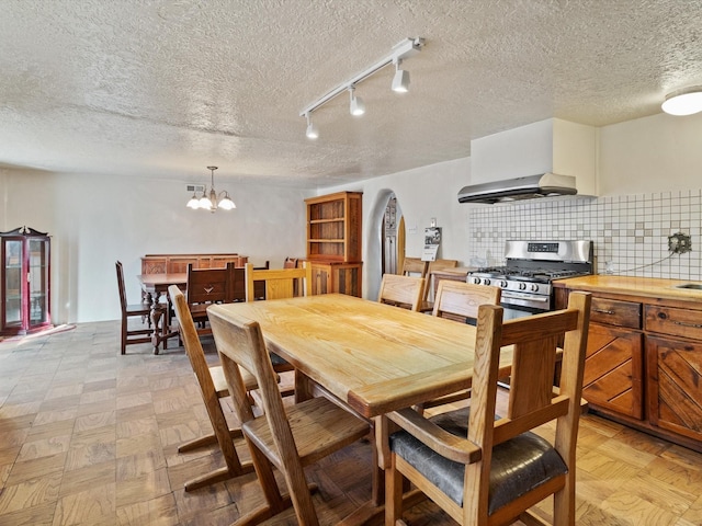 dining room with a textured ceiling, visible vents, arched walkways, and a chandelier