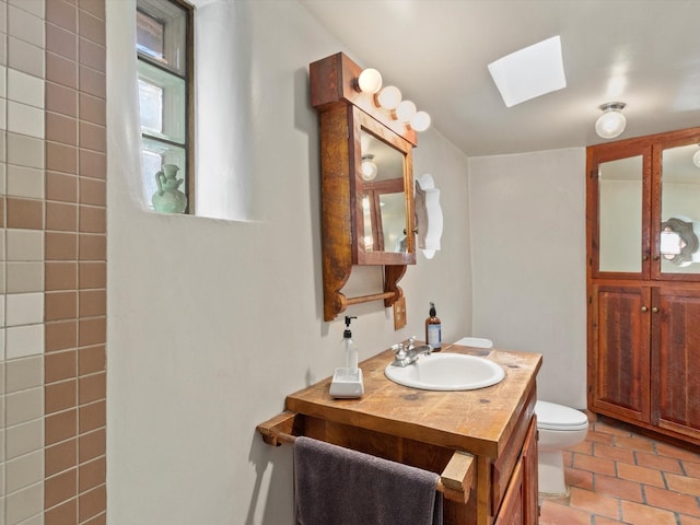 bathroom featuring tile patterned flooring, toilet, a skylight, and vanity