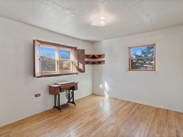 empty room with light wood finished floors and a textured ceiling